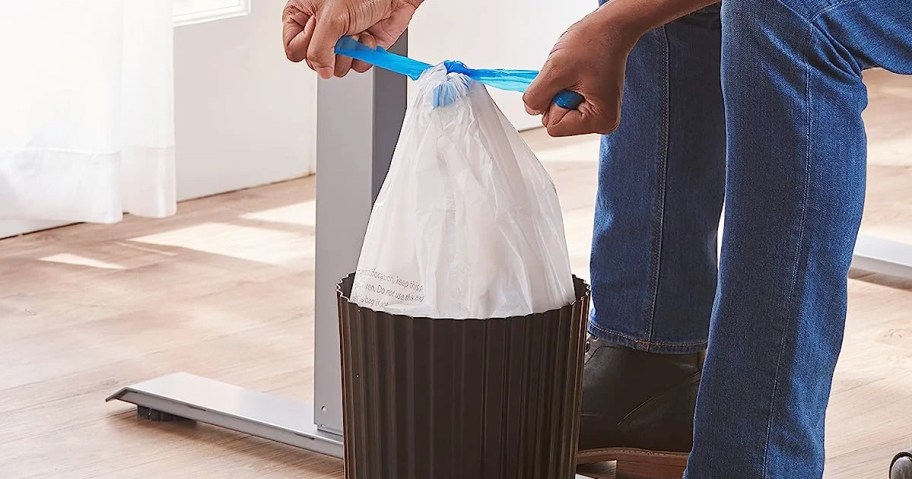 person tying drawstring on small trash bag