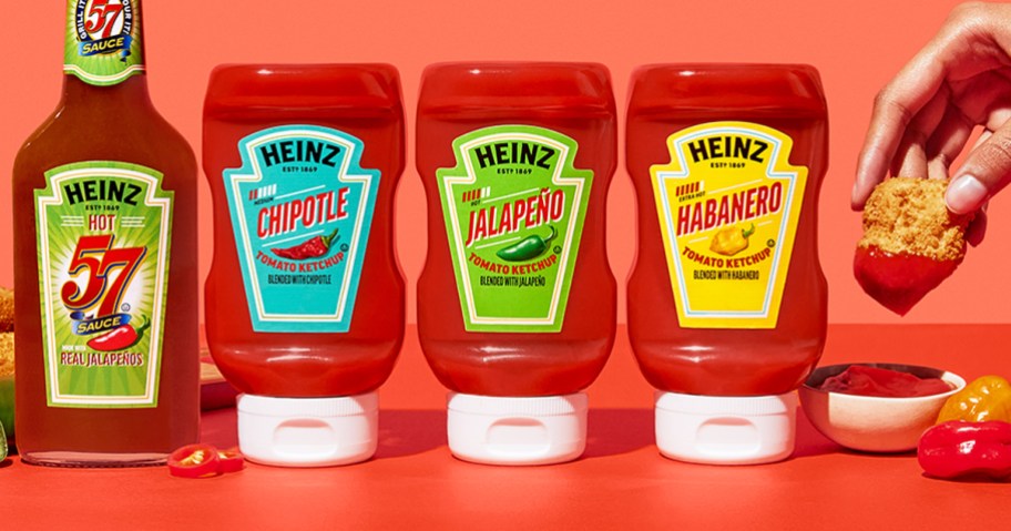 bottles of Heinz Spicy Ketchup with person dipping chicken nugget into ketchup