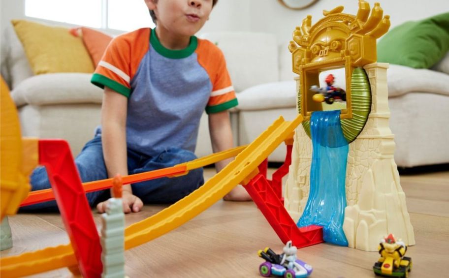 a little boy playing with a hot wheel super mario race track