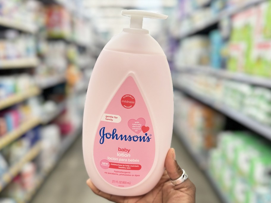 hand holding up a large pink bottle of Johnson's Baby Lotion