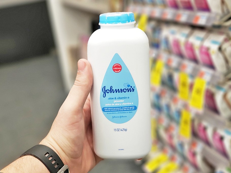 hand holding up a large white and blue bottle of Johnson's Baby Powder