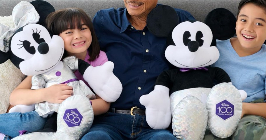 Just Play Disney 100 Years of Wonder Minnie and Mickey Mouse Jumbo Plush being held by children on a sofa