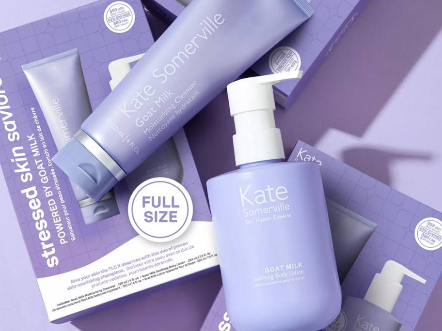 two purple bottles of Kate Somerville Goat Milk products on top of gift set packaging