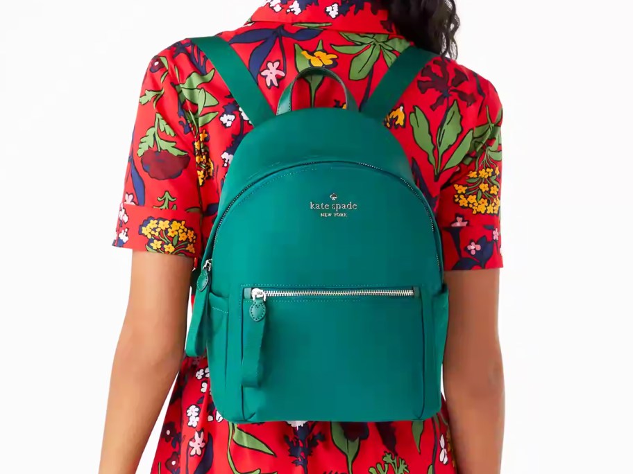 woman in red floral print dress with green backpack