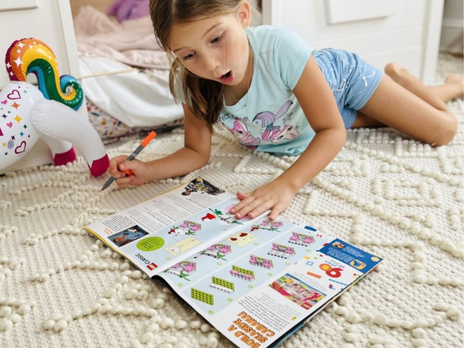 Little girl laying on the floor reading a LEGO life magazine