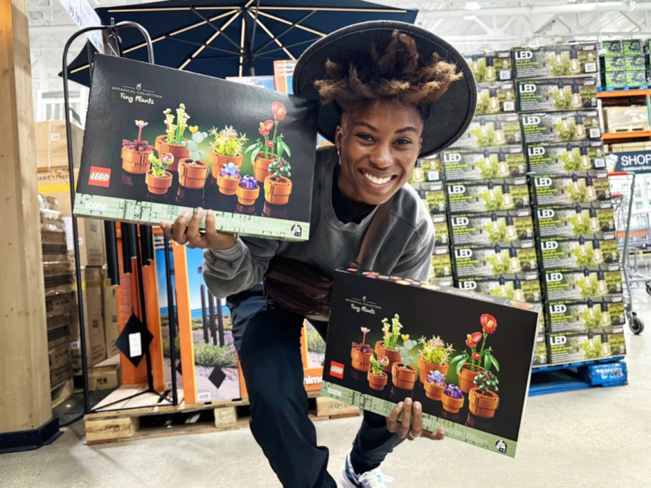 woman holding up two boxes of LEGO Tiny Plants Building Sets