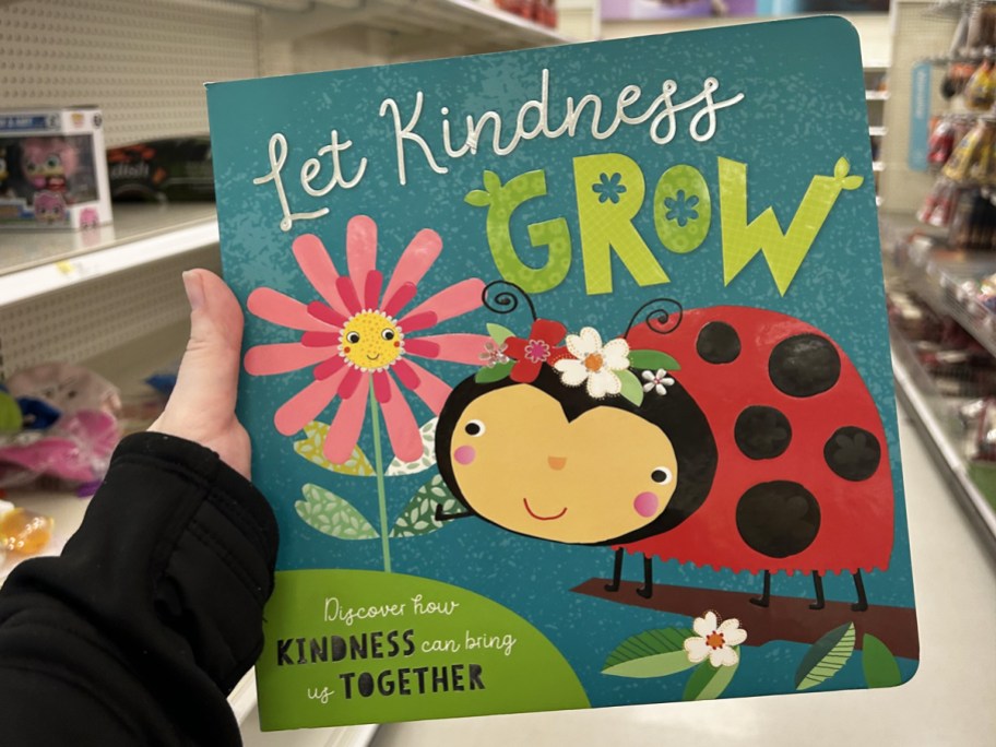 hand holding up Let Kindness Grow Book in store