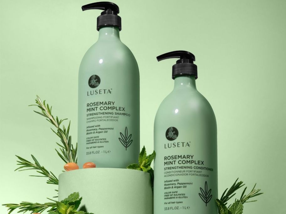 Luseta Rosemary Mint Complex shampoo and conditioner bottles on display with plants