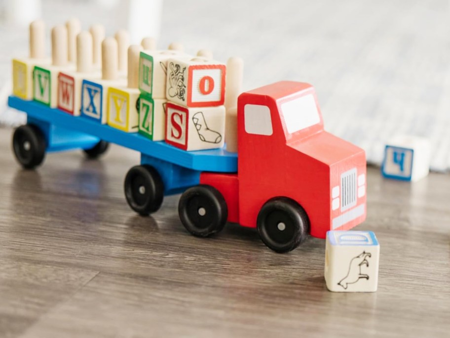 red and blue wooden truck with alphabet blocks on truck bed