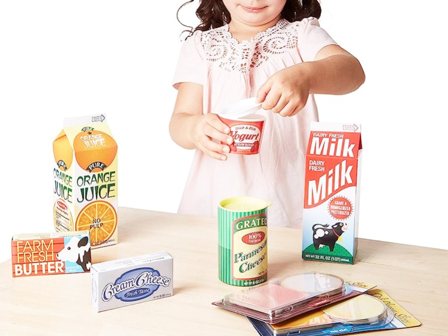 girl playing with wooden play food cartons on wood table