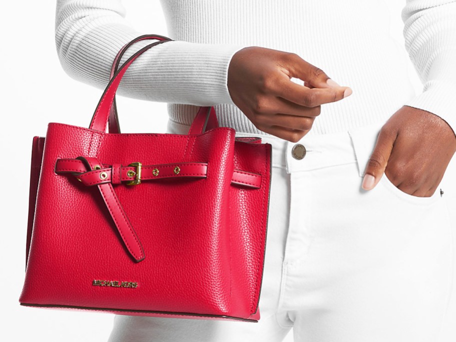 woman in an all white outfit holding a red Michael Kors bag