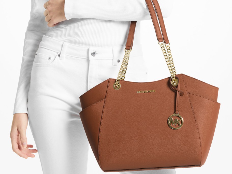woman in an all white outfit holding a brown Michael Kors bag