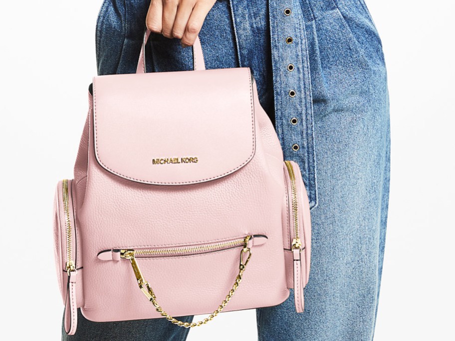 woman holding a pink leather Michael Kors backpack