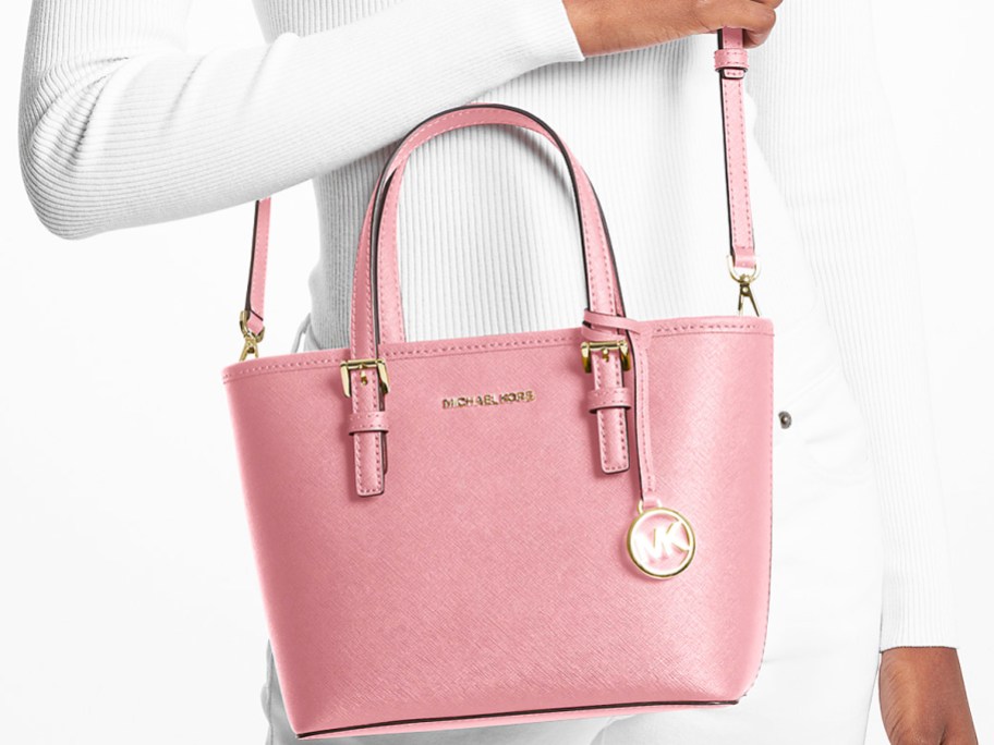 woman in an all white outfit with a pink Michael Kors crossbody bag