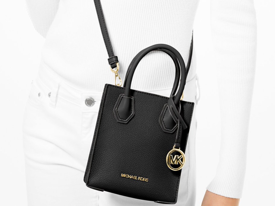 woman in an all white outfit with a small black Michael Kors crossbody bag