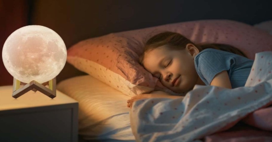 child asleep with a moon lamp on bedside table
