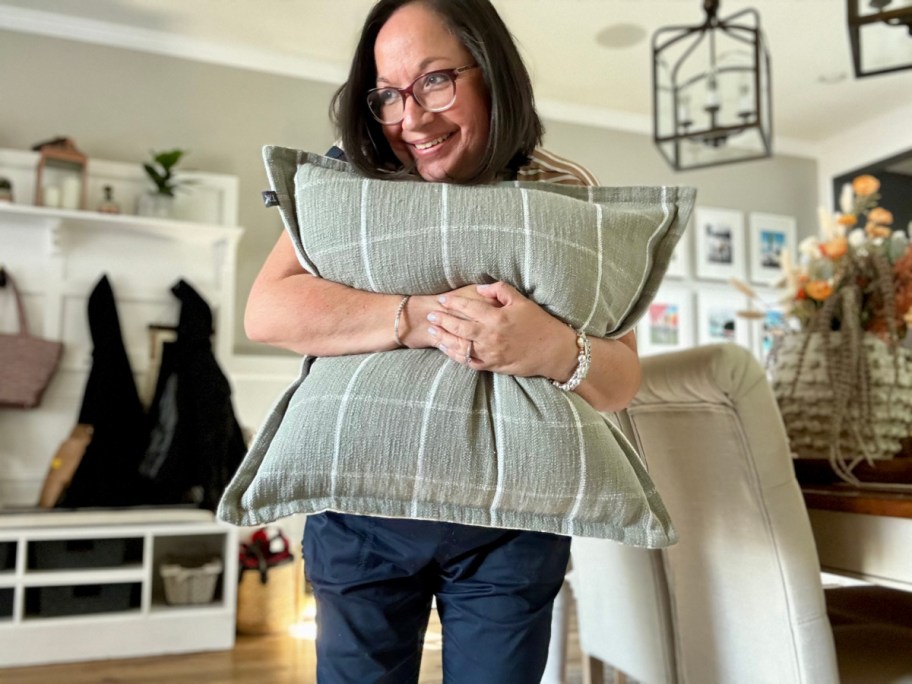 Woman hugging a gray My Texas House throw pillow from walmart 