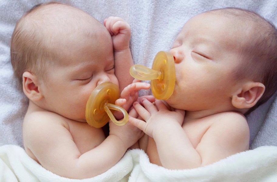 close up of two babies sleeping with white blanket sucking on Natursutten Pacifiers