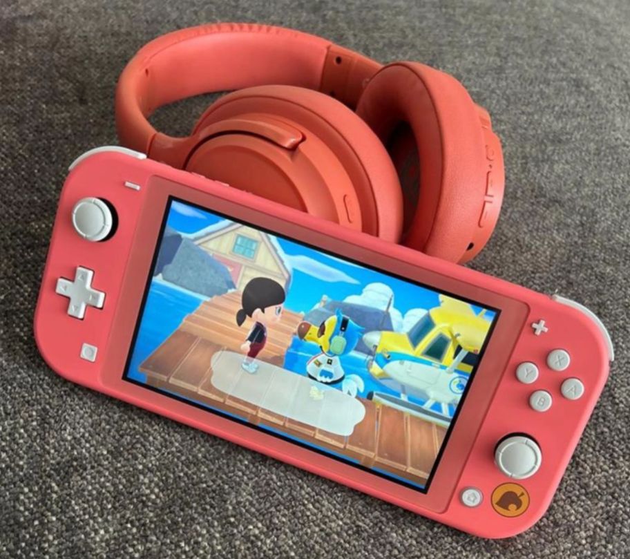 a peach nintendo switch with match over ear headphones