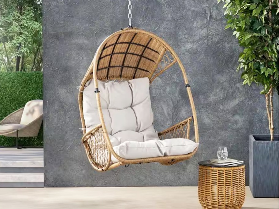 brown wicker egg chair hanging from chain on patio