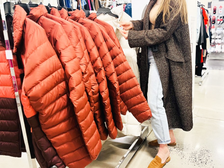 woman checking price tag on puffer jacket