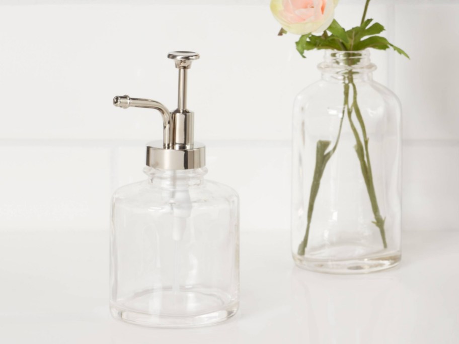 Oil pump soap dispenser displayed on top of the bathroom sink with flower in the background