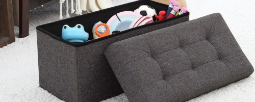 Dark gray ottoman filled with toys next to bed
