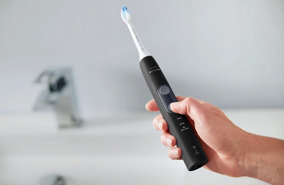 hand holding a black electric toothbrush