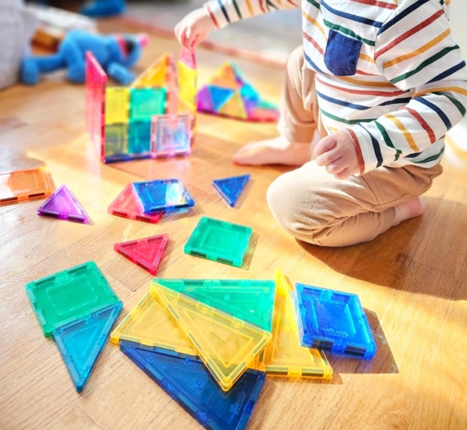 boy playing with Picasso Tiles on wood floor