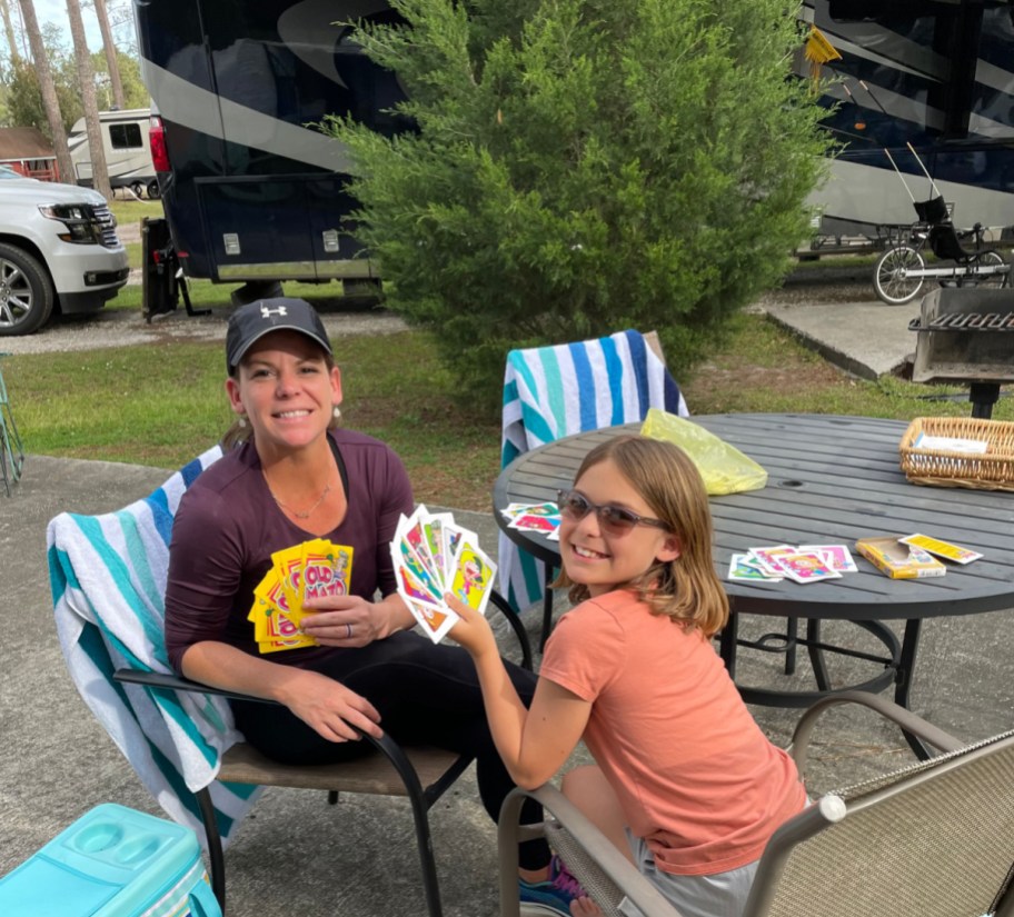a mom and daughter playing cards outside their rv rental from rvshare