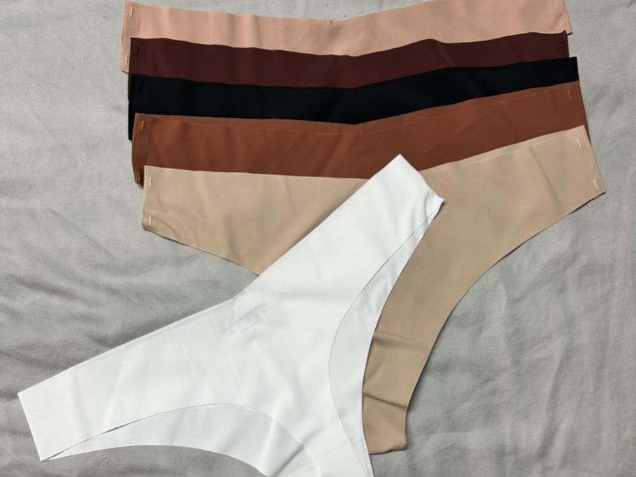 Seamless no show thong in different colors on top of the bed