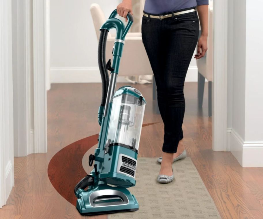 a woman vacuuming a hardwood floor with a shark navigator