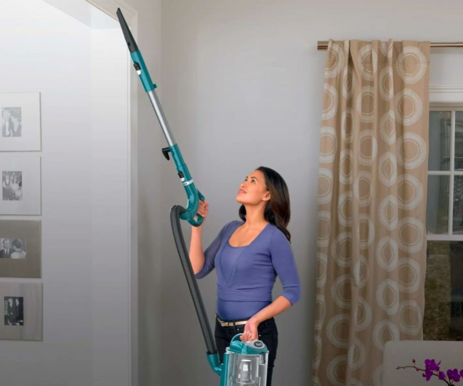 a woman vacuuming a door frame with a shark navigator