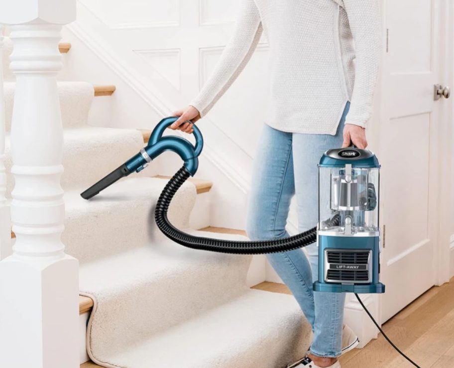 a woman vacuuming a stair with a shark navigator