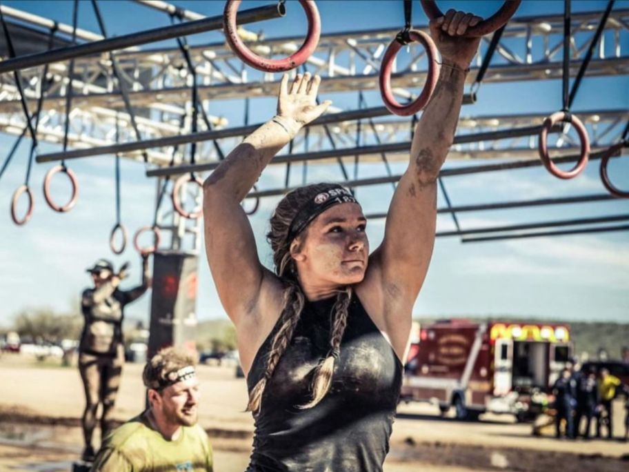 A girl competing in a Spartan Race doing a a ring course