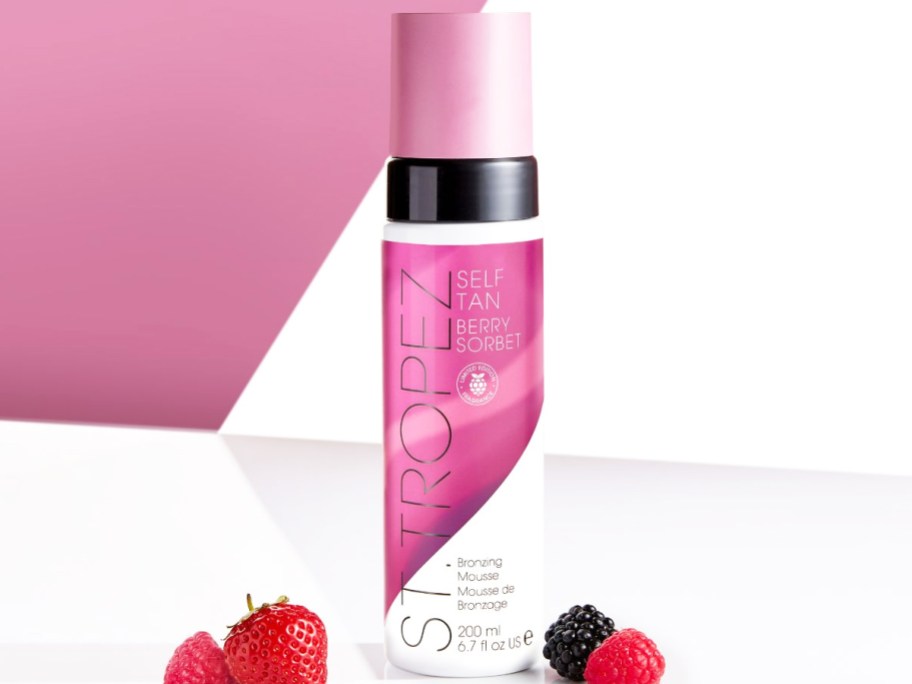 pink and white bottle of St. Tropez Self Tan Berry Sorbet near berries