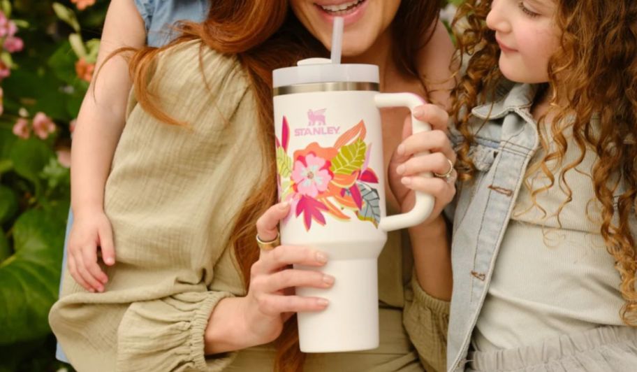 a mom drinking out of a stanly quencher tumbler with 2 little grils