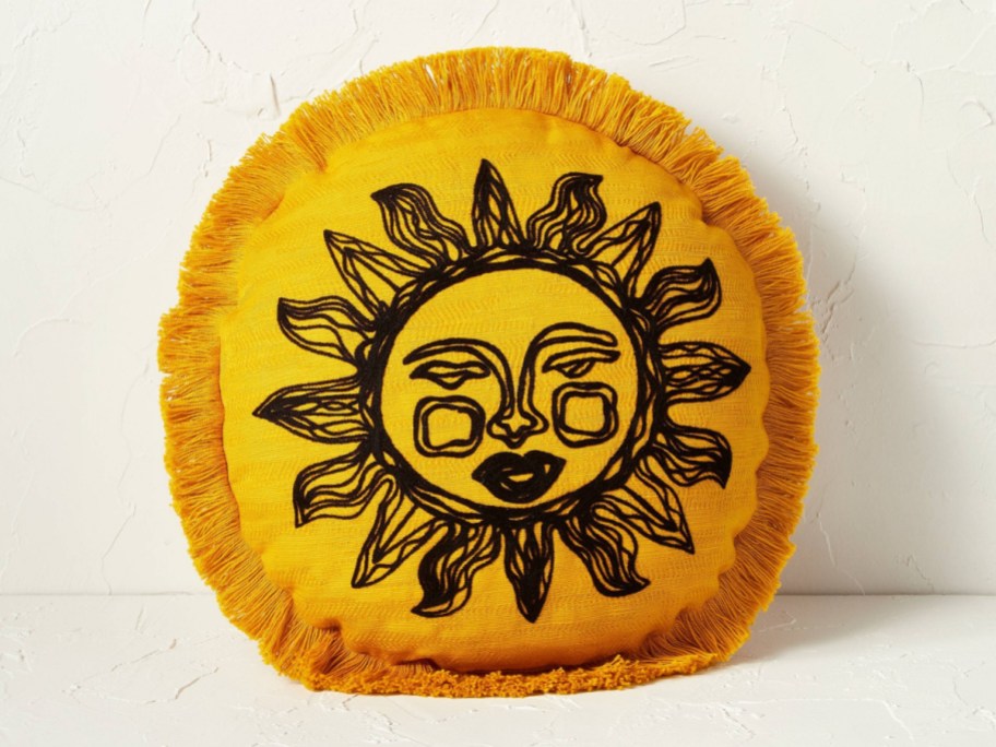 Stock image of sun decorative pillow next to the wall