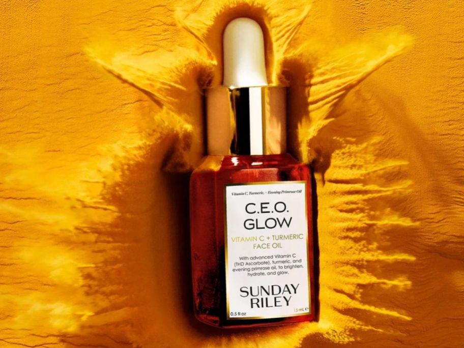 A bottle of Sunday Riley C.E.O. Glow on a golden sheet