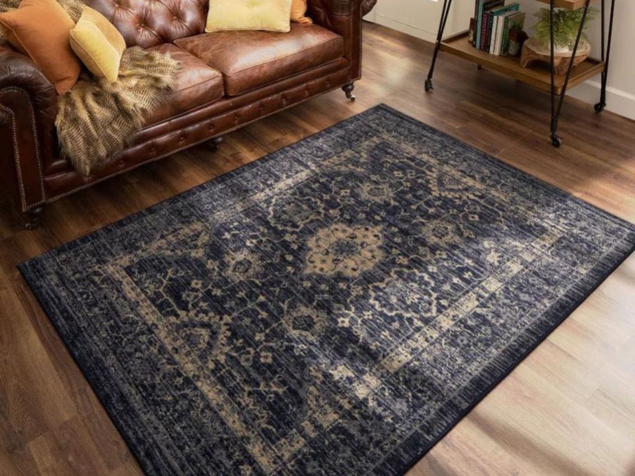 A vintage distressed style accent rug on the floor in front of a sofa