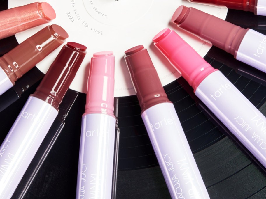 Tarte Maracuja Juicy Vinyl Lip sticks on multiple shades laying on top of a record