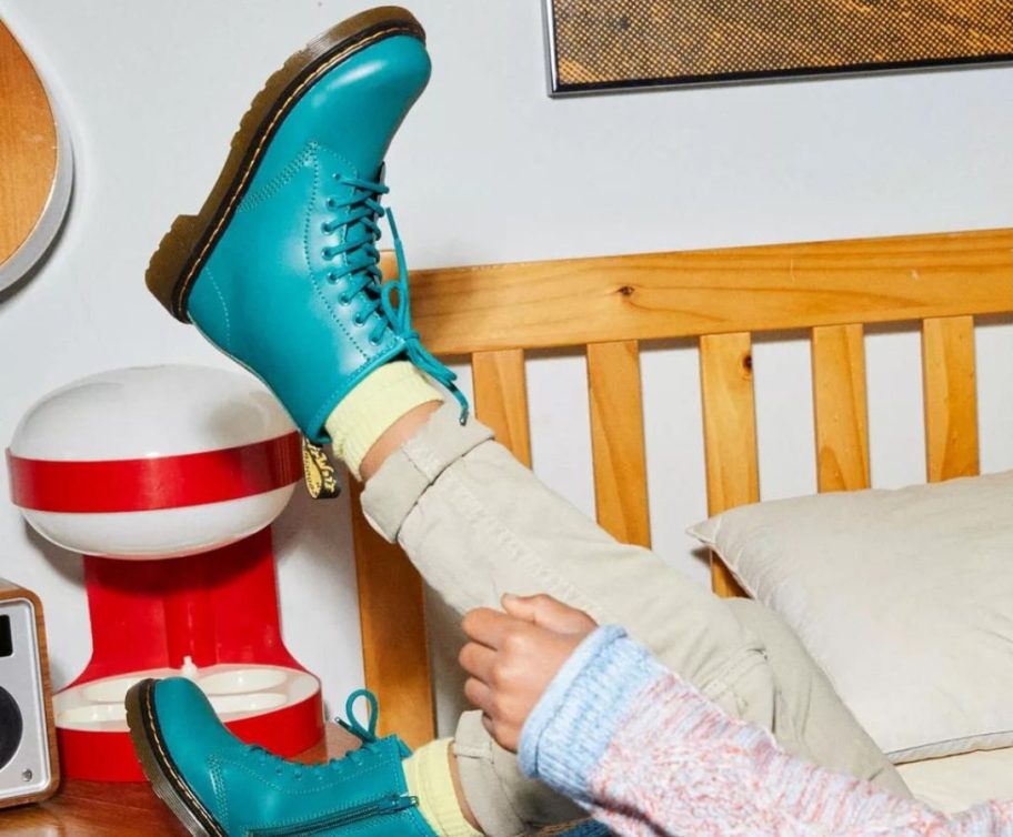 Child's legs and feet wearing Dr. Martens Teal Green Boots