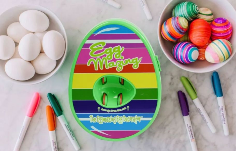 an egg spinner decorator with a bowl of undecorated eggs and a bowl of decorated eggs, along with various markers