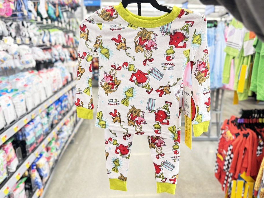 hand holding up set of christmas grinch print pajamas on hanger