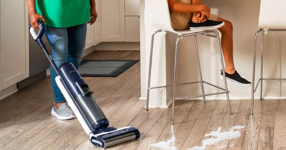 person using tineco wet/dry vacuum to clean up milk on floor