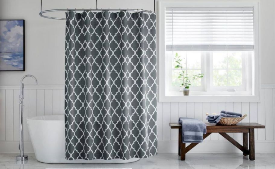 a gray and white trellis shower curtain over a tub in a bathroom next to a wooden bench