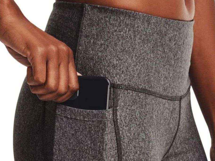 woman wearing charcoal light heather under armour leggings with phone in pocket
