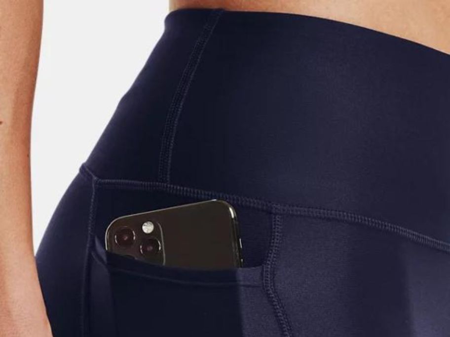 woman with phone in pocket wearing midnight navy under armour leggings