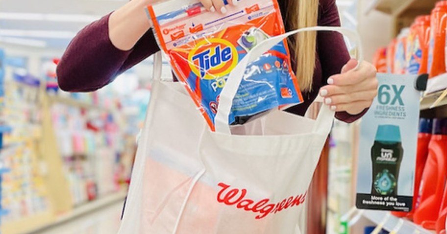 woman putting a tide pods bag into a Walgreens tote bag in store