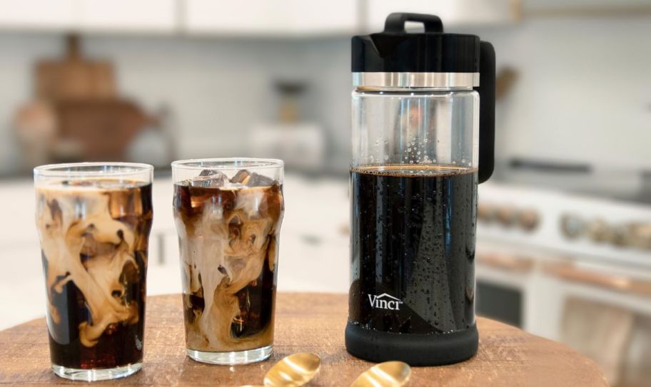 a cold brew coffee maker on a kitchen counter next to 2 iced coffees